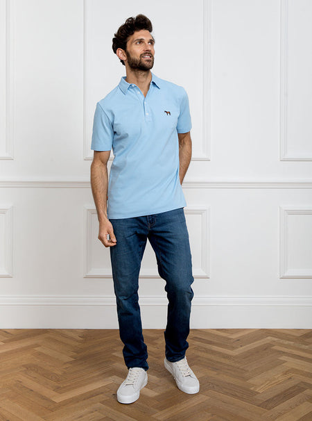 Man wearing sky blue polo shirt in 100% cotton with Newmarket 875 horse logo embroidered on the front.